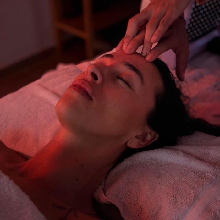 Manos de la terapeuta en el rostro durante un spa facial