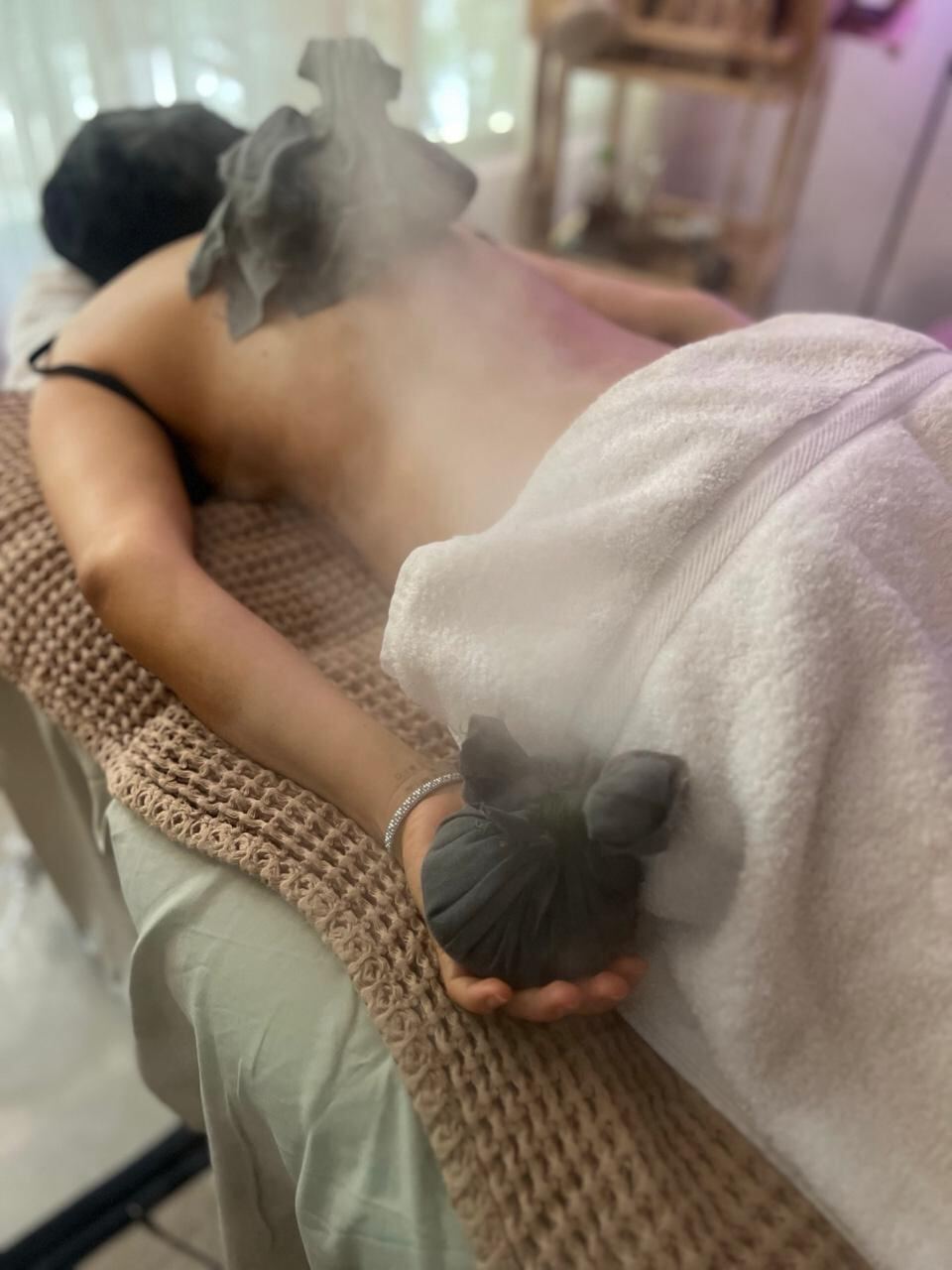 Pindas herbales calientes sobre la espalda durante una sesión